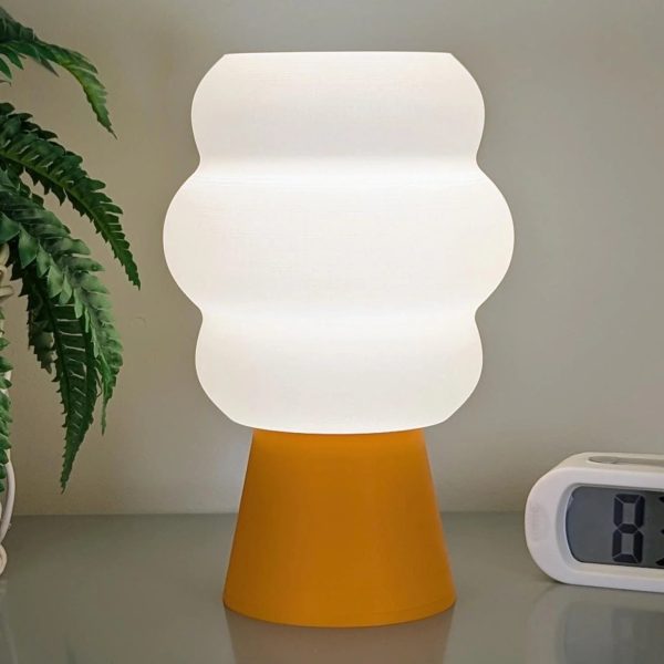Mammatus stolna lampa s toplim bijelim gornjim dijelom i narandžastom bazom na stolu