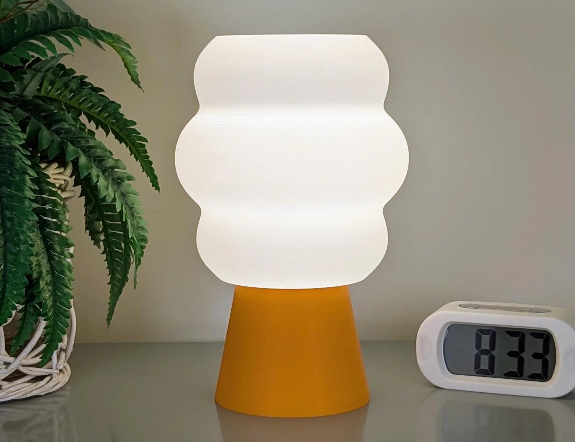 Mammatus stolna lampa s toplim bijelim gornjim dijelom i narandžastom bazom na stolu